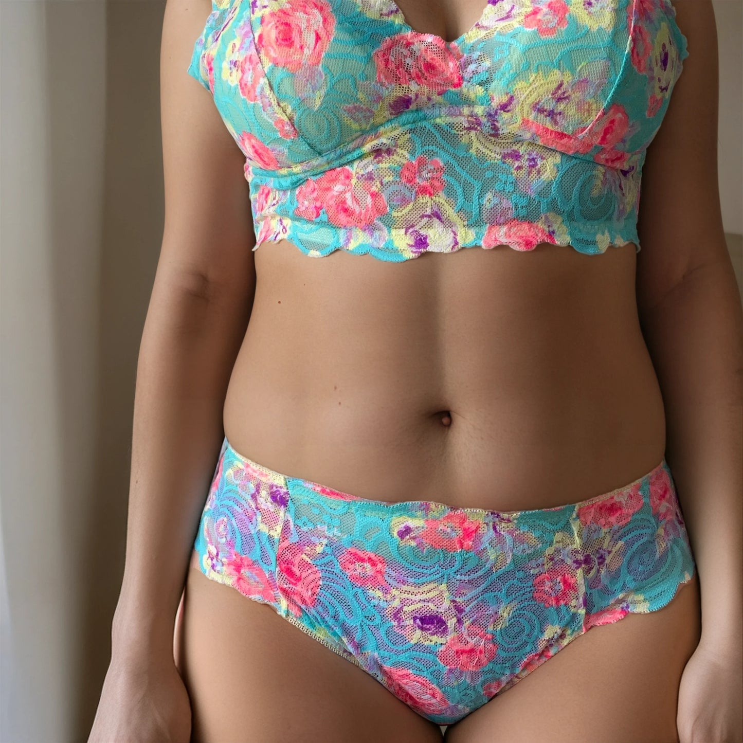 Close-up of premium European floral lace in turquoise, pink, and lilac on luxury lingerie bra.